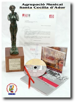 fotografia amb una composició que es composa d'una imatge de l'estatueta del guardó, una imatge del certificat o diploma acreditatiu i les caràtules externa i interna del CD Moment de Festa